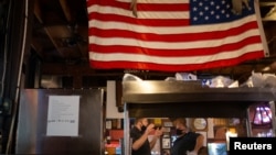 Waiters wearing protective face masks talk while working as Miami-Dade county