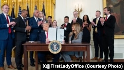在白宫东厅举行的活动中，美国总统唐纳德·特朗普和第一夫人梅拉尼娅·特朗普坐在一起，展示他们签署的“培育未来”行政命令。(2025年11月13日)