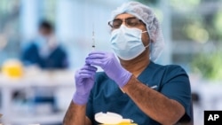 A technician prepares a Pfizer vaccine in the pharmacy area of the newly opened COVID-19 Vaccination Centre in Sydney, Australia, Monday, May 10, 2021. (James Gourley/Pool Photo via AP)
