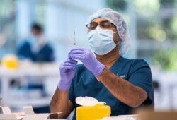 FILE - A technician prepares a Pfizer vaccine in the pharmacy area of the newly opened COVID-19 Vaccination Centre in Sydney, Australia, Monday, May 10, 2021. (James Gourley/Pool Photo via AP)