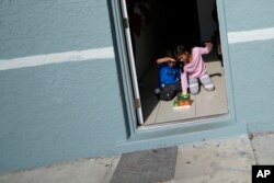 Alexa Llanos, de 7 años, a la derecha, y su hermano Alexis, de 3, juegan con una casa de juguete que recibieron como regalo de Navidad de la agencia de reasentamiento, en la casa a la que la familia se mudó en octubre de 2023. (Foto AP/Rebecca Blackwell)