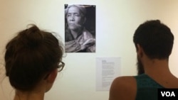 Visitors take a closer look at another fortune teller, Seim Chantha, holding three smoked cigarettes in his hand.