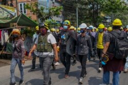 Anti-coup protesters with makeshift shields walk to take positions in Mandalay, Myanmar, Tuesday, March 9, 2021.