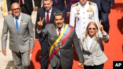 El presidente venezolano Nicolás Maduro y su esposa, Cilia Flores, saludan a su entrada al Palacio Federal Legislativo, en Caracas, este lunes, para presentar su memoria y cuenta anual. Les acompaña el presidente del parlamento, Jorge Rodríguez, a la izquierda en la fotografía.