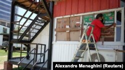 Seorang pekerja memasang pelindung di jendela-jendela sebuah bar mengantisipasi Badai Elsa yang mendekati Havana, Kuba, Sabtu, 3 Juli 2021. (Foto: Alexandre Meneghini/Reuters)