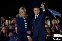 에마뉘엘 마크롱(오른쪽) 프랑스 대통령이 24일 대선 결선에서 승리, 재선을 확정한 직후 부인 브리지트 여사와 함께 파리 시내 에펠탑 앞에 모인 지지자들에게 인사하고 있다.