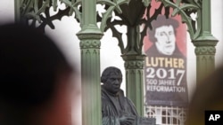 Visitors walk in front of the Martin Luther monument prior the celebrations on the occasion the 500th Anniversary of the Reformation in Wittenberg, Germany, Tuesday, Oct. 31, 2017. (AP Photo/Jens Meyer)