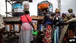 Des Congolais font la queue pour se laver les mains et faire prendre leur température dans une station de dépistage d'Ebola sur la route entre Butembo et Goma le 16 juillet 2019 - (Photo JOHN WESSELS / AFP)
