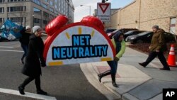 Protesters carry the top of an alarm clock display that reads "Net Neutrality" after a protest at the Federal Communications Commission in Washington, Dec. 14, 2017. (AP Photo/Carolyn Kaster)