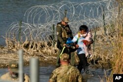 Migrantes son detenidos por funcionarios en la frontera entre Texas y México, el miércoles 3 de enero de 2024, en Eagle Pass, Texas. A NOSOTROS.