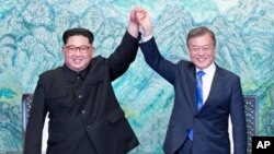 North Korean leader Kim Jong Un, left, and South Korean President Moon Jae-in raise their hands after signing on a joint statement at the border village of Panmunjom in the Demilitarized Zone, South Korea, Friday, April 27, 2018. (Korea Summit Press Pool 