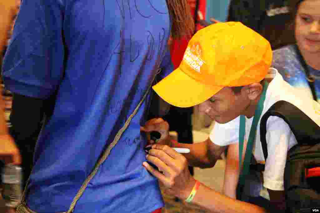 A member of the Cambodian robotics team signs on another country's team member's shirt after the closing of the First Global Challenge robotics competition in Washington, DC, Tuesday, July 18, 2017. (Nem Sopheakpanha/VOA Khmer)