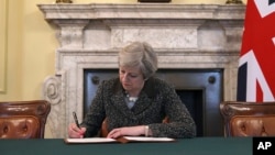 Britain's Prime Minister Theresa May signs the official letter to European Council President Donald Tusk, in 10 Downing Street, London, Tuesday March 28, 2017, invoking Article 50 of the bloc's key treaty.