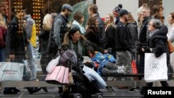 A woman sits at a bus stop with a child during Black Friday in Manhattan, New York, Nov. 25, 2016. 