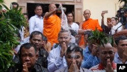 Meach Sovannara, center, a former spokesman of the opposition Cambodia National Rescue Party, receives holy water from a Buddhist monk on the outskirts of Phnom Penh, Cambodia, Tuesday, Aug. 28, 2018. Fourteen Cambodian opposition activists were freed Tue