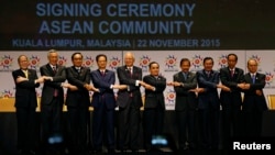 Laos' Prime Minister Thongsing Thammavong, in the middle of Asean leaders as they join their hands to pose for photographers after the signing ceremony of the 2015 Kuala Lumpur Declaration on the Establishment of the Association of Southeast Asian Nations (ASEAN) Community and the Kuala Lumpur Declaration on ASEAN 2025, in Kuala Lumpur, Malaysia, Sunday, Nov. 22, 2015. (AP Photo/Lai Seng Sin)