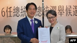 Kandidar capres Taiwan Lai Ching-te (kiri) dan tandemnya Hsiao Bi-khim (kanan)
menunjukkan dokumen pendaftaran pemilu Taiwan 2024 setelah mendaftarkan pencalonan mereka di Taipei, pada 21 November 2023. (Foto: AFP/Sam Yeh)