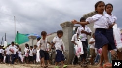 Cambodian schoolchildren walk on a muddy road near the dam site of Steung Mean Chey after they participated in an Intentional Children's Day event in the outskirts of Phnom Penh.