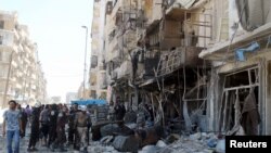 Residents and civil defense members inspect a damaged building after an airstrike on the rebel-held Tariq al-Bab neighborhood of Aleppo, Syria, April 23, 2016. 