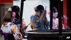 A restaurant employee wearing a protective face mask to help curb the spread of the coronavirus offer a joss sticks on a huge incense burner in the Asakusa district in Tokyo, July 27, 2020.