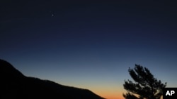 In this Sunday, Dec. 13, 2020 photo made available by NASA, Saturn, top, and Jupiter, below, are seen after sunset from Shenandoah National Park in Luray, Virginia, USA. (Bill Ingalls/NASA via AP)