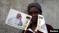 Une femme pose avec des drapeaux à l’effigie du pape François devant une église catholique à Maputo, Mozambique, le 31 août 2019.

