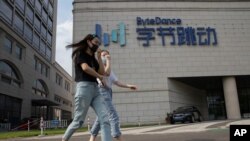FILE - In this Aug. 7, 2020, file photo, women wearing masks to prevent the spread of the coronavirus chat as they pass by the headquarters of ByteDance, owners of TikTok, in Beijing, China. TikTok's owner said Thursday, Sept. 24, 2020, that it has…
