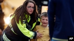 Pripadnica službi za hitne reakcije odvodi učenika u autobus u centru za rekreaciju gde su dovedeni roditeljima nakon pucnjave u školi Hajlends rač u Denveru, Kolorado, 7. maja 2019.