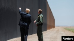El presidente Donald Trump habla con el jefe de la Patrulla Fronteriza de EE.UU., Rodney Scott, frente a un segmento del muro fronterizo con México en San Luis, Arizona, el 23 de junio de 2020.