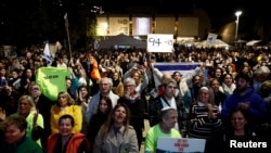 ผู้คนชมถ่ายทอดสดการปล่อยตัวประกันหญิง 3 คนแรก ในเทลอาวีฟ อิสราเอล (REUTERS/Shir Torem)