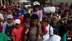 El martes 16 de octubre, en Chiquimila, Guatemala, un migrante hondureño lleva a una niña pequeña sobre sus hombros como parte de la caravana que se dirige a EE. UU. 
