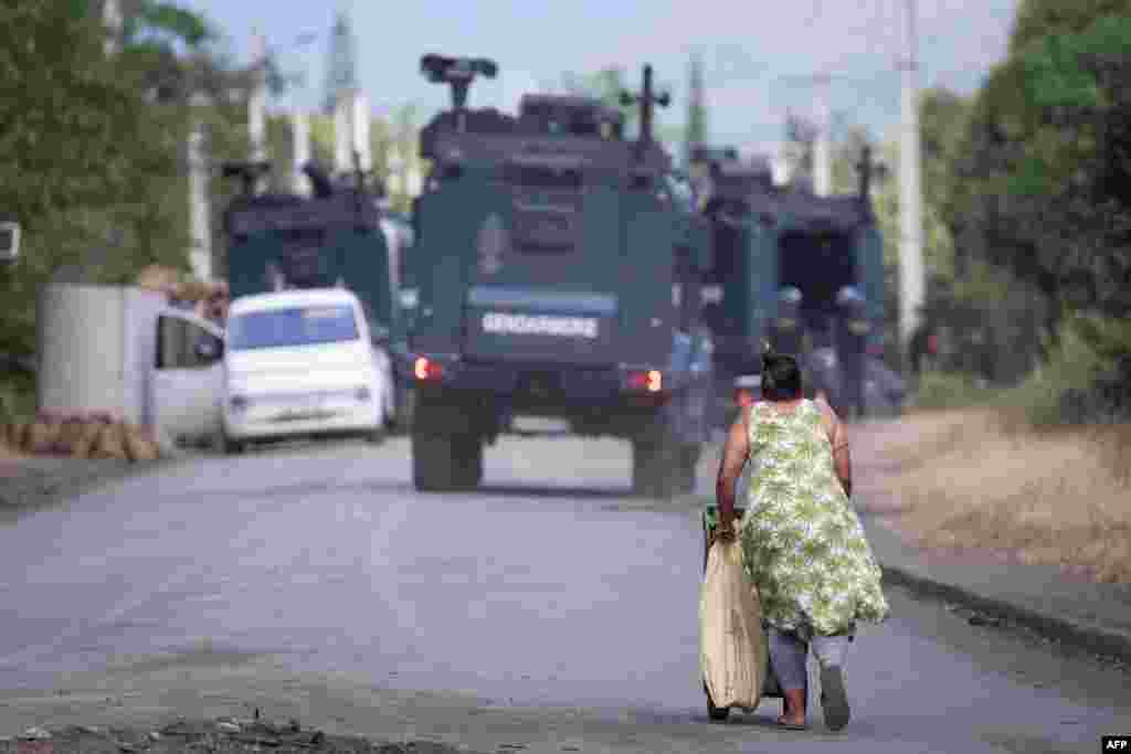 A pedestrian walks near a French gendarmerie roadblock in Saint Louis on the way to Mont-Dore, in France's Pacific territory of New Caledonia. French authorities on September 19 grappled with a new spike in violence in the country's overseas territories with security forces killing two men in New Caledonia and officials ordering a curfew after rioting in Martinique.