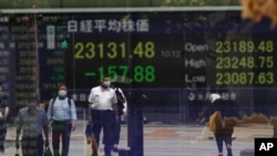 រូប​ឯកសារ៖ មនុស្សម្នា​រង់ចាំ​នៅ​ផ្លូវ​បំបែក​ ដែល​មាន​ផ្ទាំង​ខាង​ក្រោយ​បង្ហាញ​ពី​សន្ទស្សន៍​ផ្សារ​ភាគហ៊ុន​របស់​ក្រុមហ៊ុន Nikkei នៅ​ក្រុមហ៊ុន​ផ្សារ​មូលបត្រ​មួយ​នៅ​ក្នុង​ក្រុង​តូក្យូ កាលពី​ថ្ងៃទី១៧ ខែសីហា ឆ្នាំ២០២០។