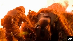 FILE - In this photo taken from a video released by the Russian Defense Ministry press service on Nov. 14, 2024, Russian serviceman fires a D-30 howitzer towards Ukrainian positions in the border area of Kursk region, Russia.