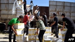 FILE - Syrian men carry aid parcels provided by the U.N. World Food Program and the Syrian Arab Red Crescent in the rebel-held town of Al-Houla, on the northern outskirts of Homs in central Syria, May 25, 2016.