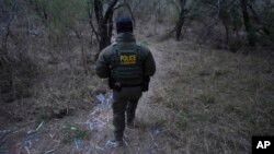 A Border Patrol agent walks along a trail littered with bracelets used by human smuggling groups near the Rio Grande at the U.S.-Mexico border, Feb. 13, 2025, in McAllen, Texas.