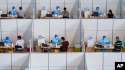 In this photo released by China's Xinhua News Agency, people get COVID-19 vaccinations at a vaccination site at a sports arena in Nanjing in eastern China's Jiangsu Province, Monday, Aug. 2, 2021. (Li Bo/Xinhua via AP)
