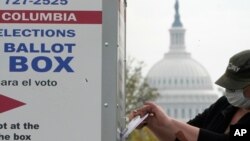 រូបឯកសារ៖ អ្នកបោះឆ្នោតម្នាក់ ទម្លាក់​សន្លឹកឆ្នោត​ដែល​បោះ​មុន​ថ្ងៃកំណត់​ទៅក្នុង​ប្រអប់​បោះឆ្នោត កាលពី​ថ្ងៃទី២៨ ខែតុលា ឆ្នាំ២០២០ នៅក្នុង​រដ្ឋធានី​វ៉ាស៊ីនតោន។