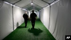 ARCHIVO - En esta fotografía de archivo del 2 de mayo de 2019, dos agentes de la Patrulla Fronteriza recorren un pasillo en un centro de detención en Donna, Texas. (AP Foto/Eric Gay, Archivo)