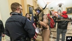 FILE - In this Jan. 6, 2021, file photo supporters of President Donald Trump are confronted by U.S. Capitol Police officers outside the Senate Chamber inside the Capitol in Washington. An Arizona man seen in photos and video of the mob wearing a fur hat w