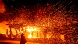 A firefighter passes a burning home as the Hillside fire burns in San Bernardino, California, Oct. 31, 2019.