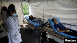 Trabajadores de la salud observan a las personas después de recibir una dosis de la vacuna contra la enfermedad por coronavirus en un centro de vacunación en San Salvador, el 13 de julio de 2021.