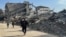 Palestinians walk past the rubble of destroyed houses during a ceasefire between Israel and Hamas in Khan Younis in the southern Gaza Strip, March 6, 2025. 