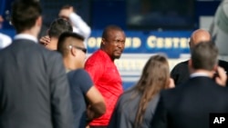 Maafisa wa Idara ya Makosa ya Jinai wa serikali kuu wanamshikilia mahabusu, wapili kutoka kushoto, mjini Los Angeles baada ya kufanya msako wa alfajiri ambao ulipelekea darzeni za watu kukamatwa Agosti 22, 2019. Wengi wa washtakiwa hao ni raia wa Nigeria.