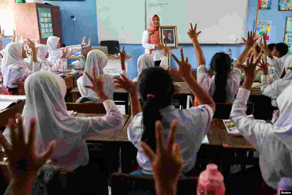 A teacher shows a portrait of Indonesia's new President Prabowo Subianto as she teaches and introduces the eighth president of the country, at the Pondok Labu Elementary School 14 Pagi, in Jakarta.