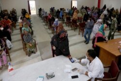 A woman scans her thumb for identification to receive cash under the governmental Ehsaas Emergency Cash Programme for families in need, during a government-imposed nationwide lockdown, Karachi, Pakistan, April 11, 2020.