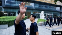 資料照：在北京的中國銀監會入口處，保安人員巡邏，一位警察對攝影者擺出姿勢，示意不讓拍照。（2018年8月6日）