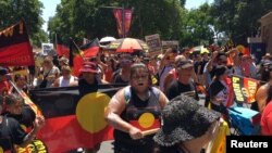 FILE - People carry Australian Aboriginal flags during a demonstration on Australia Day in Sydney, Jan. 26, 2019. 