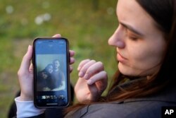 Julija Fedosjuk pokazuje svoju i suprugovu fotografiju tokom intervjua za AP u aprilu 2022. godine.