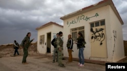 Members of the Kurdish People's Protection Units (YPG) chat together as they stand in front of a base, that used to be for Islamist Syrian rebel group Jabhat al-Nusra, after capturing it from them in Al-Rmelan, Qamshli province, Nov. 11, 2013.